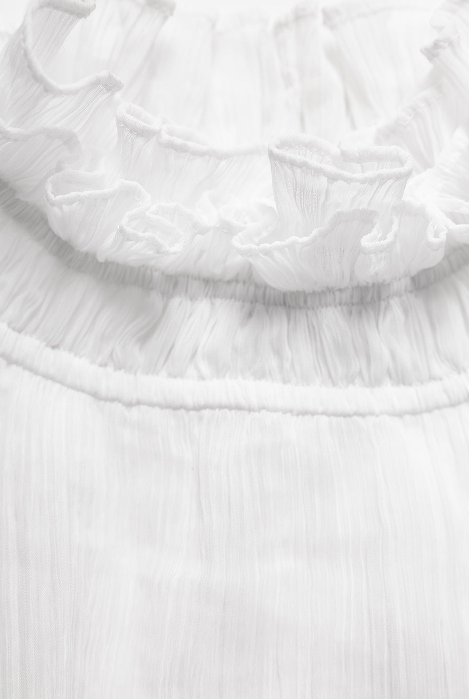 Blusa blanca de cuello alto y sin mangas con detalle plisado